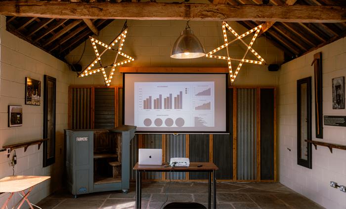 Interior of stone barn meeting space with presentation on projector screen